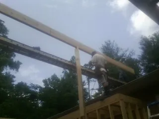Carpenter setting a ridge beam over a new addition frame — Ice Dam Removal by Roofing Brothers in Greenport