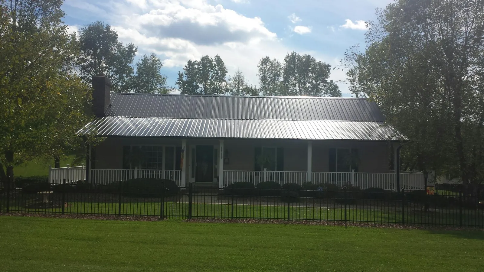 Gray metal roof on a brick ranch with a full width front porch — Gutter Guard Installation work by our crew in Greenport