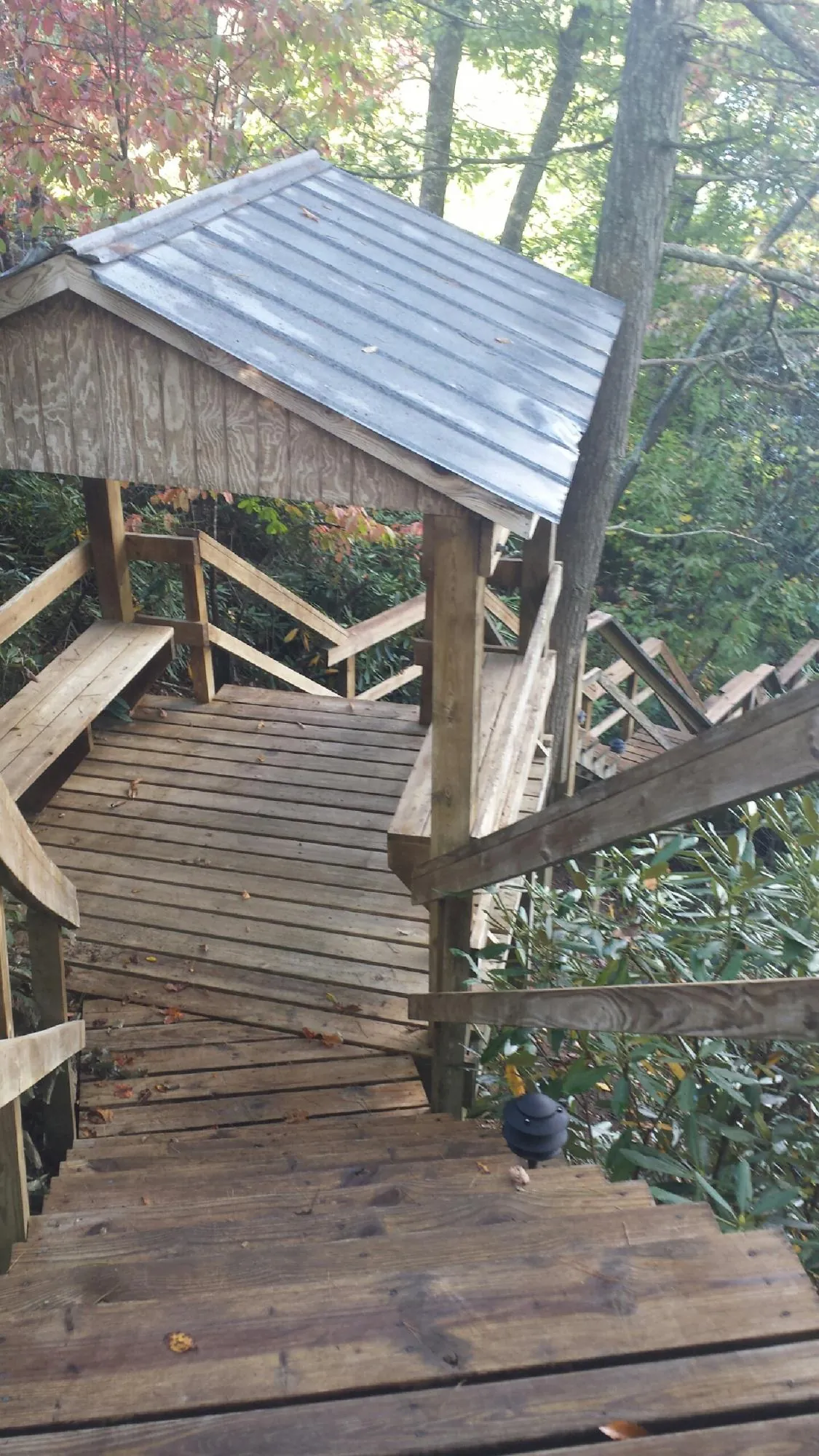 Metal roofed shelter over wooden steps on a wooded walkway — Skylight Repair & Installation work by our crew in Greenport