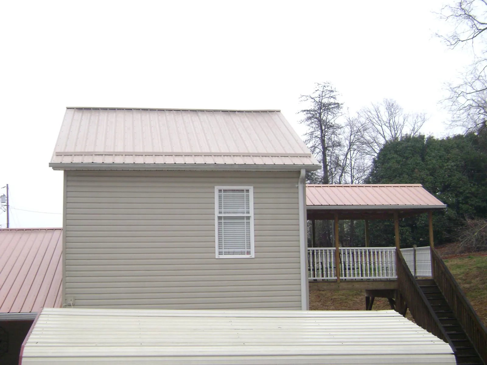 Tan metal roofs on a two story addition and attached porch, from a Roof Replacement job in Greenport