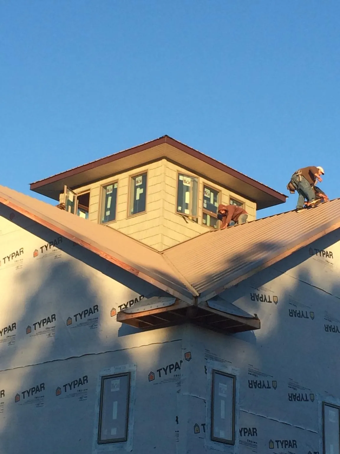 Roofers working around a rooftop cupola on a new metal roof at sunset — Roof Waterproofing in Greenport by Roofing Brothers